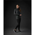 A woman in a black zip-up jacket poses with a sleek silhouette, paired with black leggings and sporty shoes.