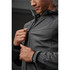 A man zips up a dark grey softshell jacket, showcasing its streamlined design and fit. The jacket has a hood and cuff detailing.