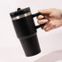 A drink bottle featuring a black double wall design with a silver band and a black lid, held by a hand.