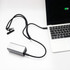 A silver charging power bank connected to a laptop with a black lanyard and cable.