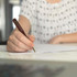 A brown pen with a baseball bat shape in use by a person writing on a sheet of paper.