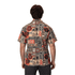A patterned button-up shirt in earthy tones featuring various tribal designs and a logo on the back.