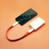 A white power bank connected to a smartphone with an orange charging cable. The phone displays a battery charging symbol.