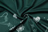 A close-up of dark green fabric featuring a pattern of white floral and gardening illustrations.