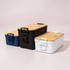 Three lunch boxes in navy blue, black, and white with bamboo lids and handles, displaying a sleek, modern design.