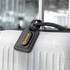A black luggage tag attached to a white suitcase, featuring a logo on its surface.