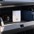A white spray and wipe cleanser with a cleaning cloth, placed inside a car's glove compartment alongside sunglasses and a dark blue pouch.