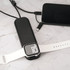 A foldable black charging cable with multiple connectors and a white wireless watch charger on a marble surface.
