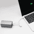 A silver power bank connected to a laptop via a white charging cable. The laptop screen shows a battery charge indicator.