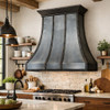 Loft style iron range hood with curved panels in a rustic kitchen
