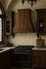 Designer copper range hood with a Gothic apron installed in a gothic style kitchen featuring dark tones and dramatic architectural details