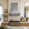 Zinc range hood with bell-shaped design and satin finish in a Mediterranean-style kitchen