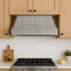 Architectural zinc range hood with flared canopy and crown detail in under mount version, smooth zinc surface with compact tapered silhouette