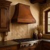 Old world copper vent hood in Old World style kitchen, smooth aged copper canopy above stone walls, rustic wood beams and traditional finishes