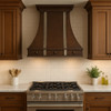 Decorative copper kitchen vent hood with silver vertical straps in transitional kitchen, hammered copper canopy above balanced cabinetry and refined stone surfaces