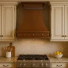 Slim copper range hood in traditional kitchen with Shaker cabinets, quiet stone and warm wood finishes