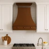 Slim copper range hood in transitional kitchen with Shaker cabinets, quiet stone and warm wood finishes