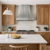 European bell-shaped zinc range hood in a modern farmhouse kitchen with warm wood cabinets