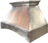 Side view of handcrafted pewter range hood with Mexican design on white background showing curved apron and riveted details