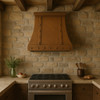 Handcrafted hacienda copper range hood with riveted straps in rustic farmhouse kitchen with wood beams
