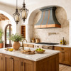 Hammered dark zinc range hood with copper apron in a Mediterranean kitchen with rustic charm