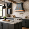Hammered dark zinc range hood with copper apron in a modern rustic kitchen with industrial accents