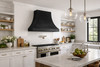 Black zinc bell range hood installed in an industrial style kitchen setting