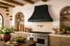 Black zinc bell range hood installed in a Spanish Revival style kitchen
