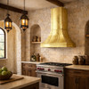 Riveted flare tin range hood with stepped base in an Old World kitchen with stone walls, dark wood, and iron hardware