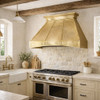 Tin range hood in European farmhouse kitchen with crown top, riveted bands, painted cabinets and stone walls