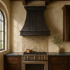 Dark zinc range hood with flared canopy and seamless straps in a kitchen setting