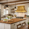 Riveted tin bell canopy range hood in rustic farmhouse kitchen with shaker cabinets, white tile, reclaimed wood beams