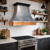 Polished zinc range hood with copper straps and apron in a transitional kitchen with an industrial flavour