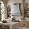 Natural zinc range hood in large Organic Modern kitchen with limestone island, pale wood cabinets and textured plaster walls