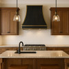 Sculpted black zinc bell range hood with copper straps in Southwestern kitchen with terracotta tones and iron accents