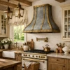 Antique zinc range hood with brass straps and rivets in a French Country kitchen with painted cabinets and limestone