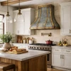 Antique zinc range hood with brass straps and rivets in a transitional rustic kitchen with Shaker cabinets and warm wood