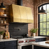 Hammered wall brass range hood with riveted straps in industrial classic kitchen with brick, steel accents and simple cabinets