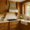 Handcrafted brushed zinc range hood with brass straps in a traditional style kitchen setting