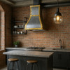 Central island handcrafted brushed zinc range hood with brass straps in a industrial style kitchen