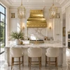 Gold brass range hood with polished rivets in a bright Neoclassical kitchen with marble and paneled cabinetry