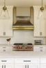 30 inch zinc metal range hood with brass straps in a transitional kitchen