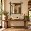 Hand-forged iron mirror with cross corner finials above a rustic wood console with artisan decor
