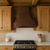 Random hammered copper range hood in a farmhouse kitchen with light cabinetry and rustic finishes