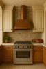Old-World copper range hood with cylindrical chimney in a Mediterranean kitchen with plaster walls, arches, and patterned tile