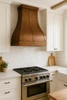 Sweep copper range hood in a modern farmhouse kitchen with white oak cabinets, quartz countertops, and exposed wood beams