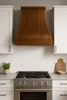 30-inch sweep copper range hood in a contemporary kitchen with slab cabinetry, porcelain surfaces, minimal hardware, and linear lighting