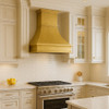 Brushed brass range hood with classic crown molding in a luxury kitchen with custom cabinetry