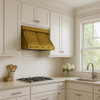 Brass trapezoid range hood with riveted straps in a traditional suburban kitchen with warm cabinetry