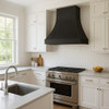 Black zinc kitchen range hood with trapezoidal canopy 36" in a bright transitional kitchen with white cabinets and large window light